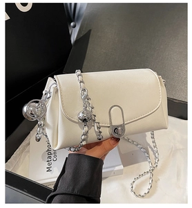 Détail du sac beige avec bandoulière en chaîne argentée et pendentif boule en métal
