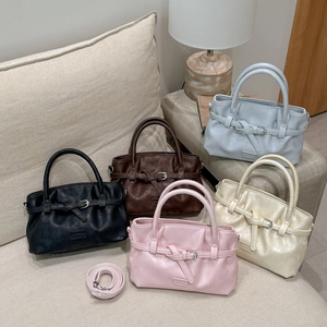 Close-up of five stylish faux leather bucket bags in neutral colors on a cozy sofa