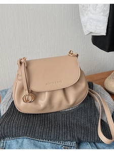 Détail du sac bandoulière beige avec boucle anneau dorée et logo tendance imprimé