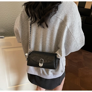 Détail du sac à chaîne noir avec fermoir ovale argenté et pendentif sphérique décoratif