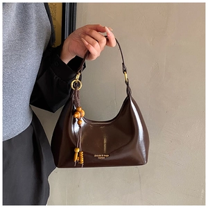 Detalle de bolso medialuna marrón brillante con cuentas de madera y herrajes dorados