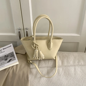 Détail du sac seau beige clair avec pendentif à franges et finition en cuir synthétique