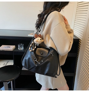 Detail view of black matte leather tote bag with magnetic flap pocket and bear charm