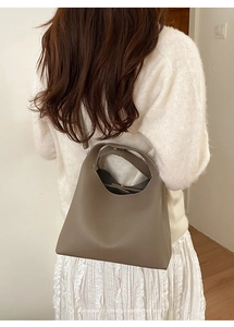 Detalle del bolso bowling de cuero grano lichi topo con diseño de asa ancha minimalista