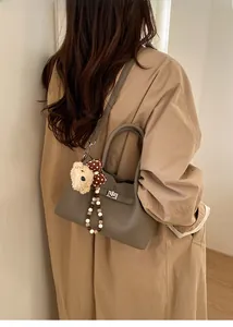 Détail du sac seau en cuir gris avec un pendentif ours et une boucle en métal élégante