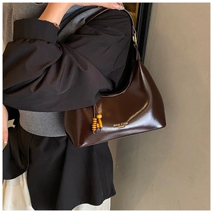 Detalle del bolso hobo marrón oscuro con acabado brillante y adorno de madera