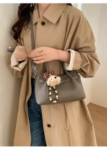 Détail du sac seau en cuir gris avec boucle argentée et pendentif ours en peluche