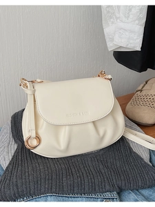 Détail du sac à bandoulière en cuir blanc crème avec base plissée et anneaux dorés