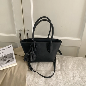 Gros plan du sac seau noir mat avec un pendentif à franges et une texture en cuir PU lisse