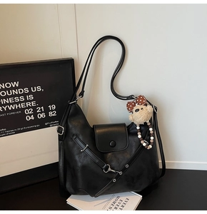 Detail of black matte PU leather tote bag with silver buckle and plush bear charm