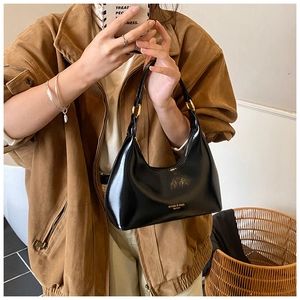 Bolso de hombro negro acharolado con detalles dorados y logotipo grabado en la base