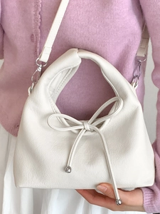 White soft leather shoulder bag with a bow detail and silver beads shown on a model