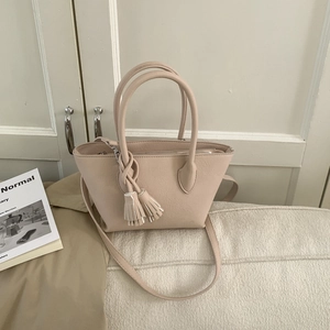 Détail du sac seau beige minimaliste avec décoration de pompon et texture fine