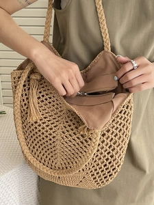 Sac cabas en crochet beige avec franges et poche intérieure zippée sur une table blanche