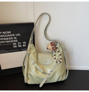 Detail of light green crescent tote bag with bear charm and decorative bead chain