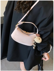 Pink crescent shoulder bag with gold clasp and plush sheep charm on black blazer