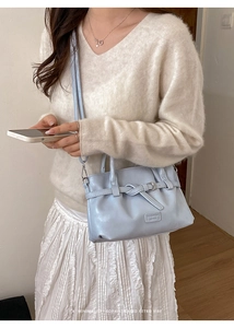 Detail of light blue faux leather bucket bag with brand plaque and adjustable strap