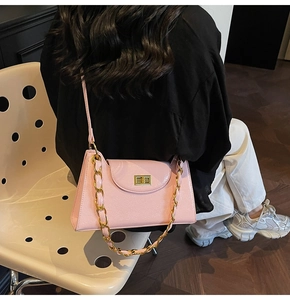 Detail of light pink patent leather shoulder bag with golden chain and twist lock