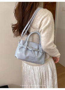 Close-up of a light blue leather handbag with decorative buckle and logo detail