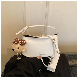 Detail of white half-moon crossbody bag with teddy bear charm and gold metal hardware