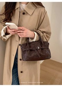 Detail of vintage brown leather handbag with fashion tag shown in hand by model