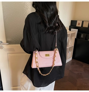 Detail of pink shoulder bag with glossy texture, golden twist lock and chain strap