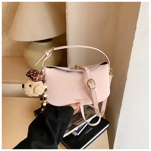 Pink crossbody dumpling bag with a cute plush dog charm on a cozy lifestyle background