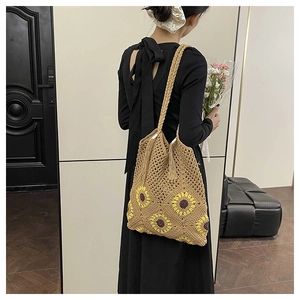 Gros plan sur un sac cabas tissé avec motifs de tournesols jaunes et détails de franges