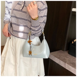 Detalle del bolso de montura azul claro con dije de madera y herrajes metálicos dorados