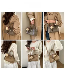 Détail du sac seau en cuir à texture litchi avec un charmant pendentif d'ours doux