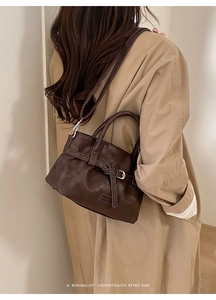 Detail of dark brown leather bucket bag shown on a beige trench coat for a minimalist retro look