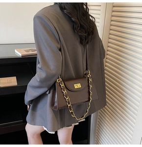 Detailed close-up of dark brown vintage underarm bag with glossy finish and gold chain strap