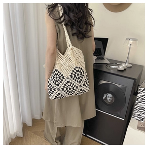 Détail d'un sac cabas au crochet avec motifs floraux noir et blanc et pompons décoratifs