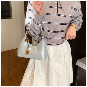 Detalle de bolso hobo azul claro con borla de cuentas de madera y letras doradas