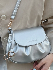 Sac à bandoulière argenté métallisé plissé avec logo FASHION & BAGS sur fond beige neutre