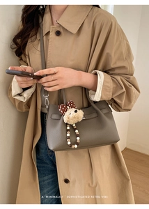 Détail du sac seau en cuir gris avec un pendentif ours en peluche et cordon de serrage