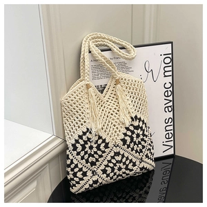 Détail d'un sac cabas crocheté main avec motifs géométriques noirs et breloque pompon