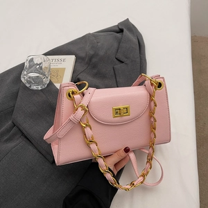 Detailed view of a pink textured faux leather baguette bag with a gold chain and lock