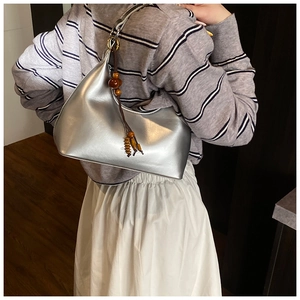 Detail of silver metallic hobo bag featuring a decorative wooden bead tassel accent