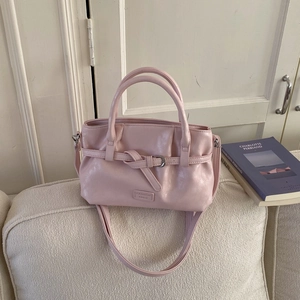 Pink pleated bucket bag with gold hardware detail on a textured sofa background