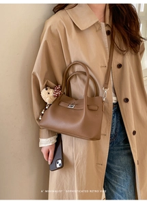 Détail du sac seau rétro en cuir marron avec breloque d'ours en peluche sur l'anse
