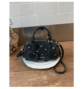 Détail du sac baguette noir avec rivets en étoile et un pendentif en forme de cœur