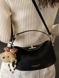 Fashionable black leather dumpling bag with golden lock and cute plush bear charm