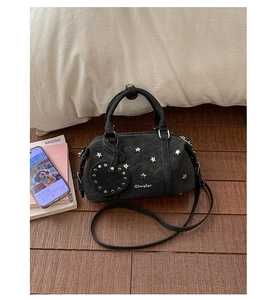 Détail du sac Boston en daim noir avec clous étoiles dorés et pendentif cœur