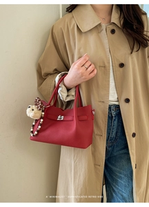 Détail d'un sac à main rouge en cuir grainé avec fermoir argenté et pendentif lapin