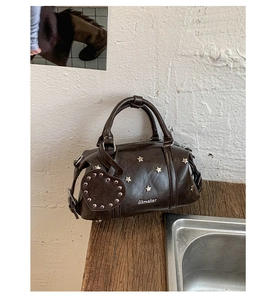 Détail du sac Boston marron rétro avec clous en étoile argentés et breloque en cœur
