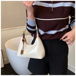 Detalle del bolso hobo blanco en forma de media luna con borla de cuentas y logo dorado