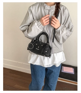 Détail du sac Boston noir avec clous en forme d'étoile argentée et logo sur le devant