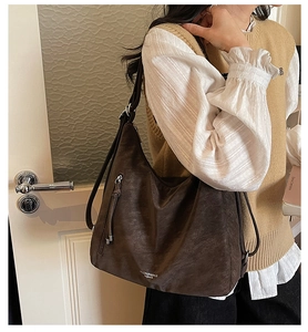 Detailed close-up of dark brown tote bag with matte leather texture and silver zipper detail