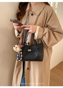 Détail du sac seau en cuir grainé noir avec fermoir rotatif argenté et breloques de sac